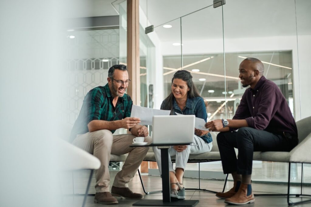 hree business professionals reviewing documents and a laptop, symbolizing a consultation for bridge financing solutions for a business in the Toronto area.
